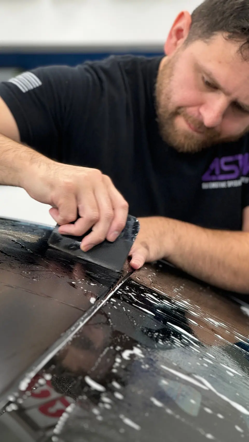 Installer laying satin black PPF on a Mercedes-AMG
